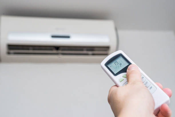 istock Hand with remote control directed on the conditioner on the wall. Air conditioner with remote controller. 1206982743