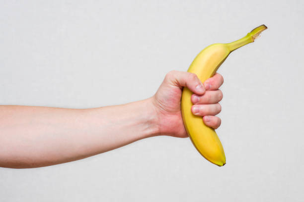 la mano del giovane che tiene una bella banana fresca e gialla. mano maschile che tiene una banana. - men banana holding cut out foto e immagini stock