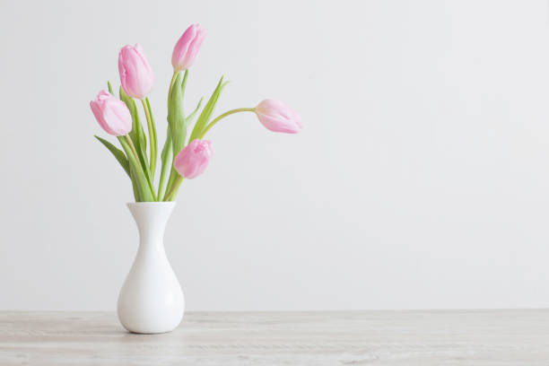 istock pink tulips in white ceramic vase on wooden table on background white wall 1206984736