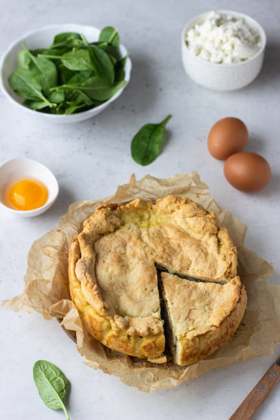 istock Spinach, chicken and ricotta pie with fresh spinach leaves, ricotta and eggs on a light stone background. 1206985681