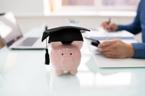 istock Pink Piggybank With Graduation Cap Near Documents 1206990186
