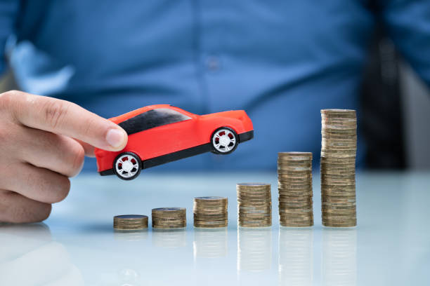 istock Person Holding Car Over Rising Stacked Coins 1206990335