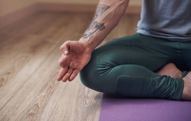 Choose to be here now Cropped shot of an unrecognizable man sitting indoors alone and meditating with his hand in a gyan mudra man yoga tattoo stock pictures, royalty-free photos & images