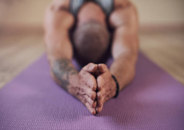 Taking a moment to breathe Cropped shot of an unrecognizable man holding a child's pose during an indoor yoga session alone man yoga tattoo stock pictures, royalty-free photos & images