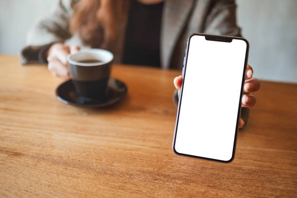 istock a businesswoman holding and showing black mobile phone with blank white screen while drinking coffee in cafe 1206992429