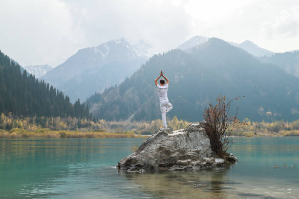 istock A zen man in white practices yoga in nature. Pose Vrikshasana or tree pose 1206992842