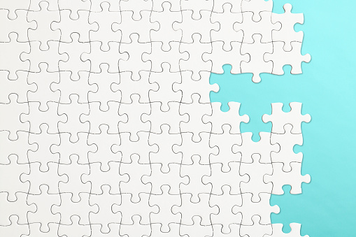 White blank jigsaw puzzle on light blue background with copy space.
