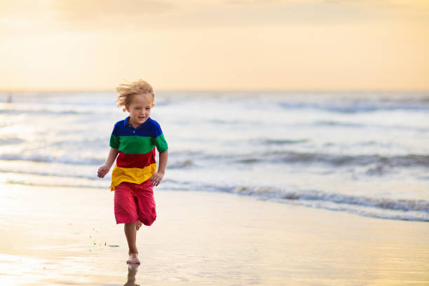 istock Child playing on ocean beach. Kid at sunset sea. 1206994740