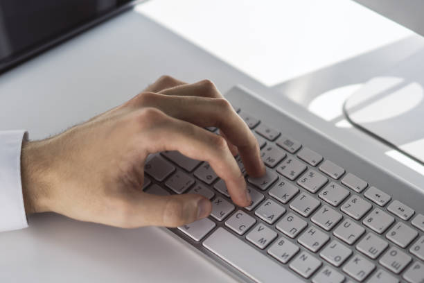 istock Male hands typing on computer keyboard in sunny office, business and technology concept. Close up 1206995925