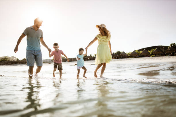 istock Young happy family having fun while running through sea. 1206997100
