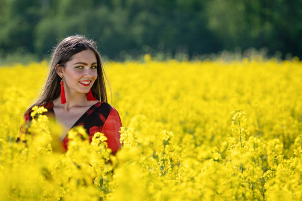 istock Young woman standing in yellow oilseed rape field image 1206997157