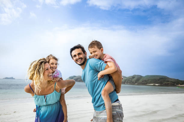 istock Playful family having fun while piggybacking on the beach. 1206998251