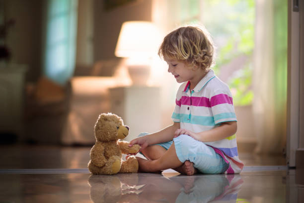 istock Child playing with teddy bear. Kid and toy at home 1207000425
