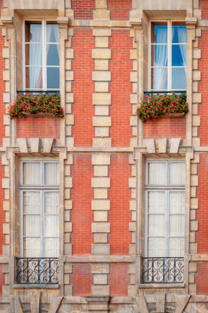 Windows with flowers and facade of building on Place des Vosges in Paris
