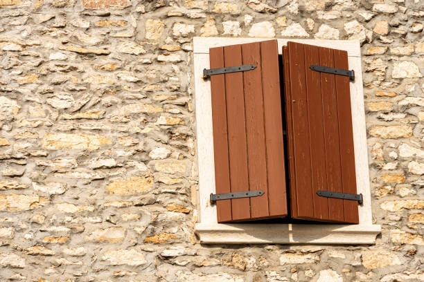 Close-up of a window with closed wooden shutters on a stone wall. Veneto, Verona province, Italy, Europe