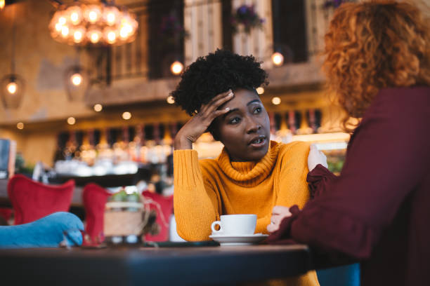 Two female friends talking about a problem one of them has. The red haired girl is supportive and understanding while the other is talking. stock photo