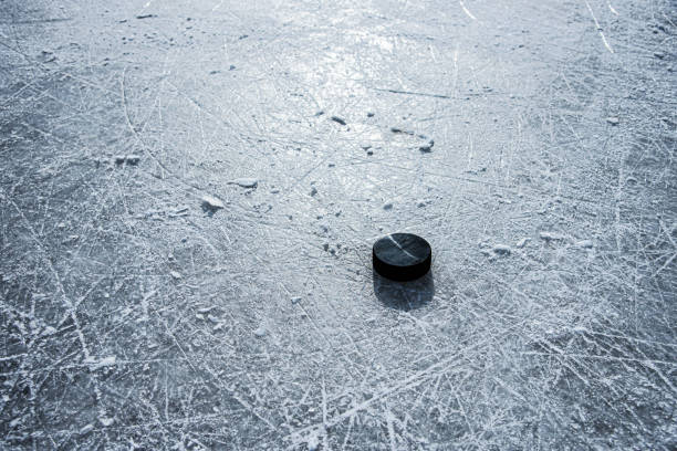 istock black hockey puck lies on ice at stadium 1207005461
