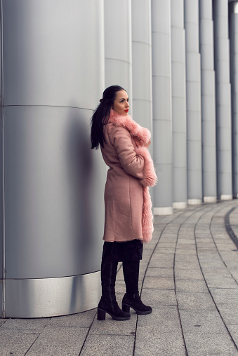 Brunette in the city in a pink coat