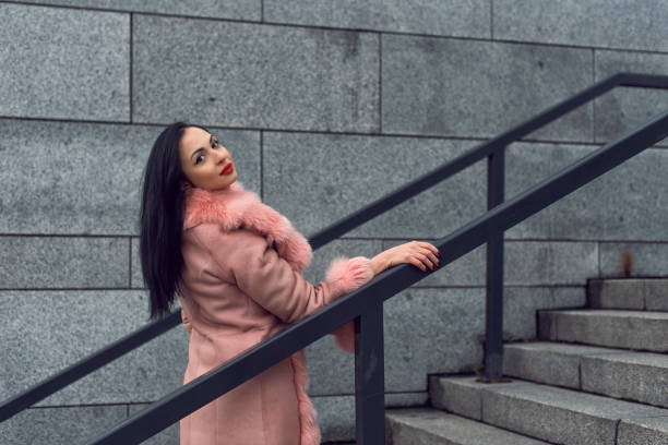 istock Brunette in the city in a pink coat 1207005720