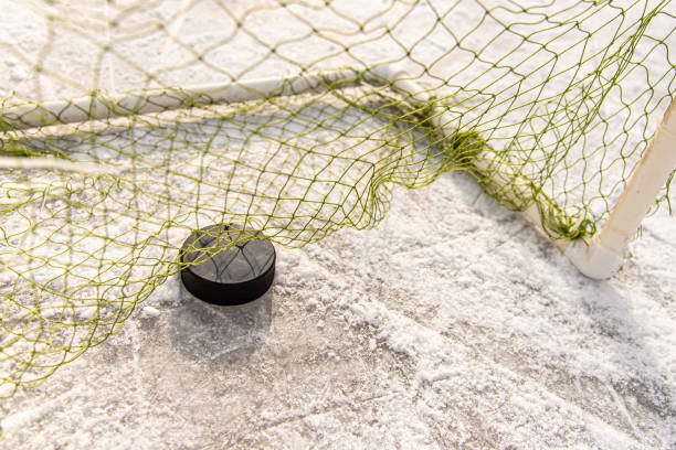 hockey puck in the goal net close-up - ice hockey hockey puck playing shooting at goal imagens e fotografias de stock