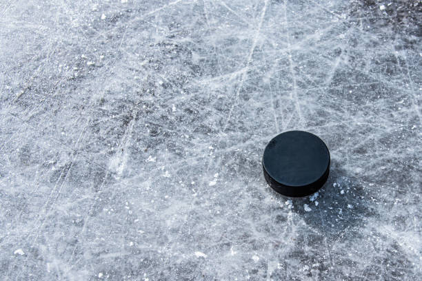 istock black hockey puck lies on ice at stadium 1207005821