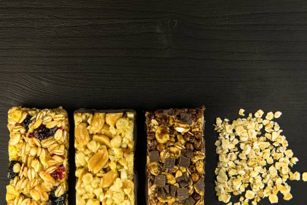 istock Granola bars with roasted nuts, selective focus. Oatmeal bar with nuts on black background. Nutrition for athletes. Vegetarian sweetness. 1207008353