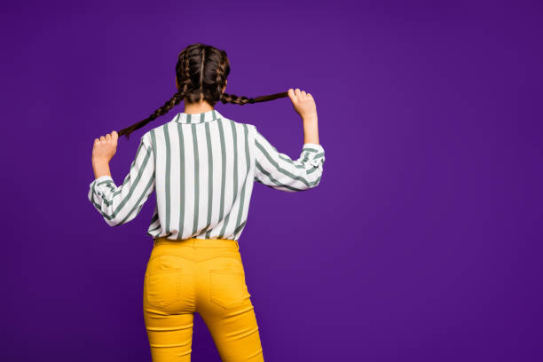 dietro la vista foto di bella bella signora che tiene le trecce mani nascondendo il viso persona timida indossare camicia a righe pantaloni gialli isolato sfondo di colore viola - codini foto e immagini stock