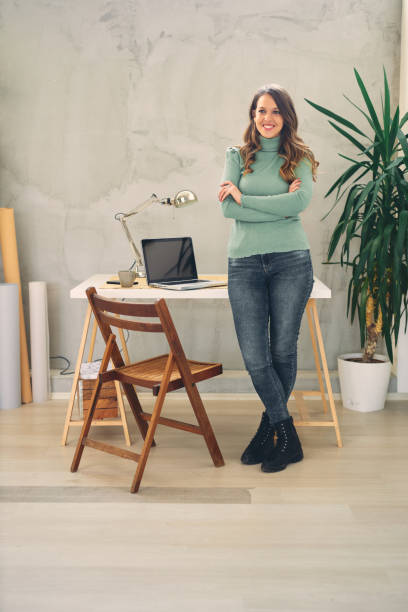 istock Young attractive female standing in modern office and looking at camera. 1207009630