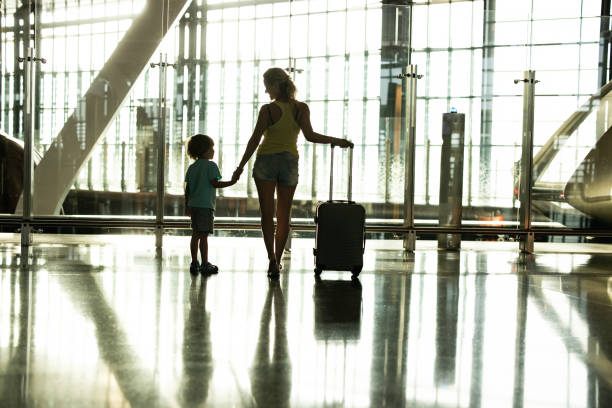 istock Back view of happy single mother and son walking at terminal. 1207011052