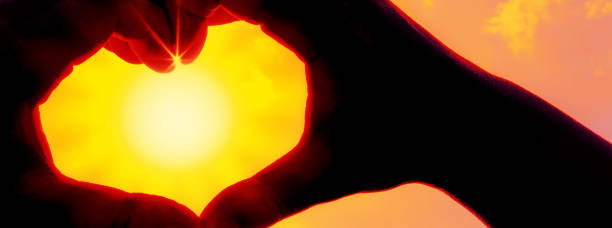 istock Hands forming a heart shape over the sun 1207011359
