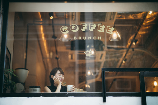 Beautiful young Asian woman having a relaxing time enjoying coffee in a cafe