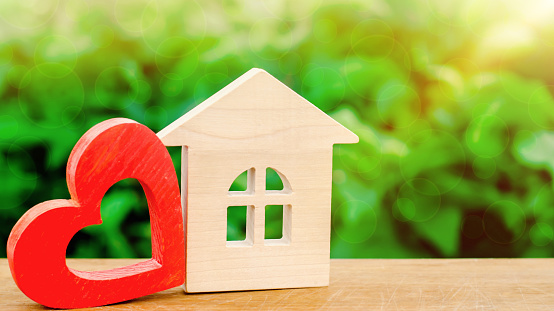 Wooden house and red heart. Concept of sweet home. Property insurance. A new home for family. Rent a house on Valentine's Day. Family comfort. Affordable mortgage housing for young couples.