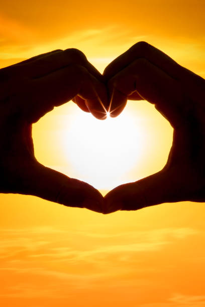 istock Hands forming a heart shape over the sun 1207012998