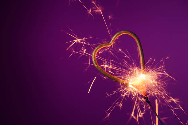 istock Burning sparkler in love heart shape on a purple background 1207014862