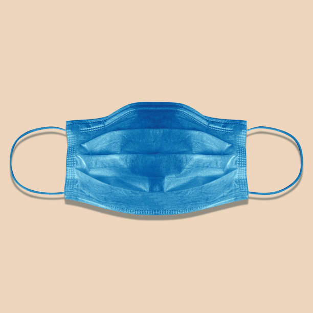 masque médical typique à 3 ply isolé sur le rose. dure éclairée, ombre dure. masque chirurgical bleu de boucle d’oreille. masque chirurgical avec sangles d’oreille en caoutchouc pour couvrir la bouche et le nez. masque de procédure des bactéries - boucle doreille photos et images de collection