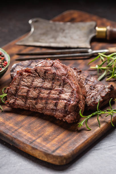 istock Two beef rump steaks with herbs tomatoes salt and spices on butcher board 1207020178