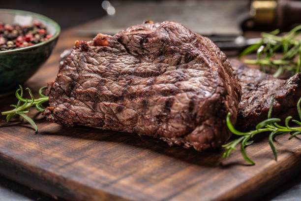 istock Two beef rump steaks with herbs tomatoes salt and spices on butcher board 1207020212