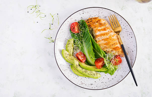 huhn gegrilltes filet mit salat frische tomaten und avocado. gesunde ernährung, ketogene ernährung, diät-mittagessen-konzept. keto/paleo diät-menü. ansicht von oben, flach liegend - kohlenhydratarme diät stock-fotos und bilder