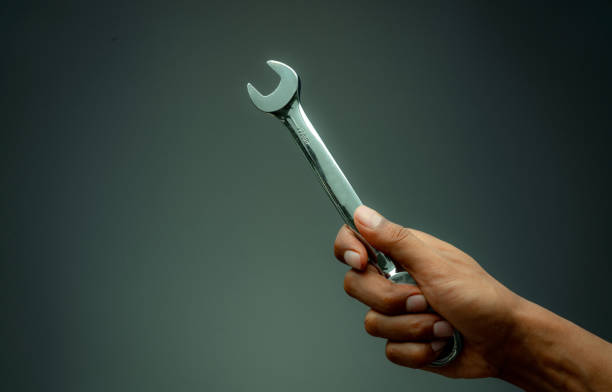 istock Technician hand holding chrome wrench. Plumber or mechanic technician work with spanner in hand. Mechanic tools. Service and maintenance machine in factory concept. Car or motorcycle fix or repair. 1207022941