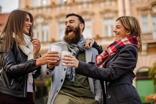 Low angle view of happy friends laughing and enjoying a drink in a public area