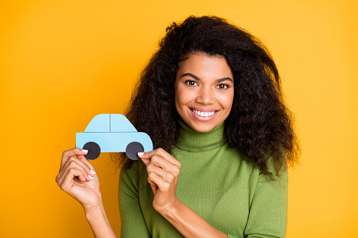 Photo of cheerful fun positive cute pretty nice girlfriend adverting you auto services her company, provides holding paper car with hands isolated vivid color background