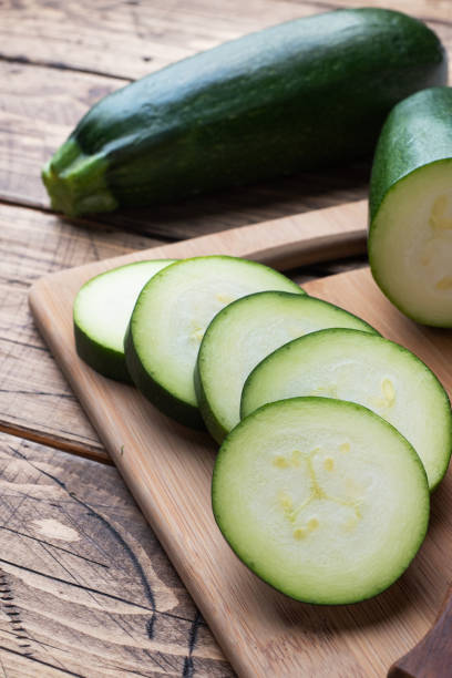 istock Fresh green zucchini cut into slices on a cutting Board. Wooden rustic table background. 1207031126