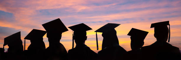 silhouetten von studenten mit graduiertenkappen in einer reihe auf sonnenuntergang hintergrund. abschlussfeier auf universitäts-web-banner. - urkunden fotos stock-fotos und bilder
