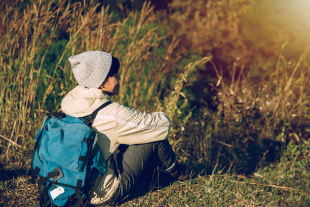 istock Asian young man backpackers sitting on the grass in mountains with river enjoying their alone outdoor, lifestyle travel adventure, people hiking vacations in Thailand. 1207034067