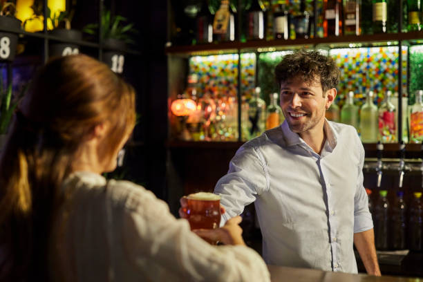 istock Smiling bartender serving beer to customer in club 1207035073