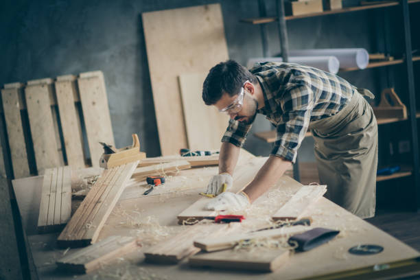istock Profile side view portrait of his he nice attractive focused skilled experienced hardworking guy self-employed builder carving wood on table desk at modern industrial loft brick style interior indoors 1207037644