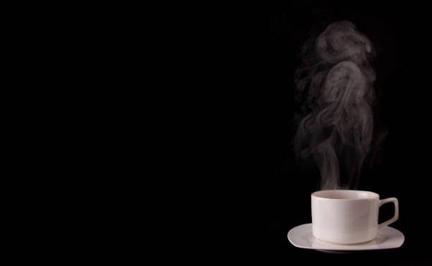 istock White coffee cup on plate with smoke isolated on black background in studio With copy space. 1207037730