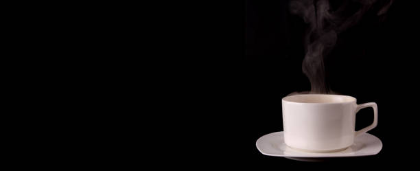 istock White coffee cup on plate with smoke isolated on black background in studio With copy space. 1207037732
