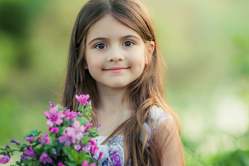A child of 7-9 years collects a bouquet of wild flowers at outdoors