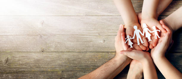 istock Family Care Concept - Hands With Paper Silhouette On Table 1207040819